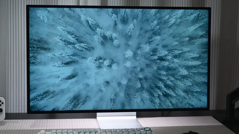 Front view of the Kuycon P32K monitor on a desk, showing an aerial view of a snowy forest