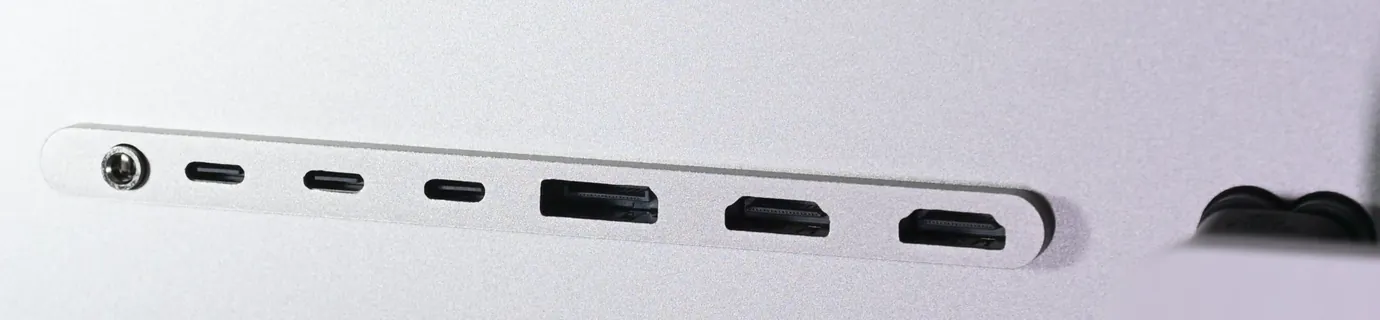 Close-up of the row of connectors on the back of the Kuycon P32K: a headphone jack, three USB-C ports, a DisplayPort, two HDMI ports, then the power socket